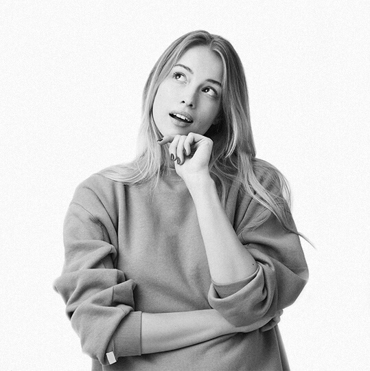 Young woman in a sweater looking thoughtfully upward.