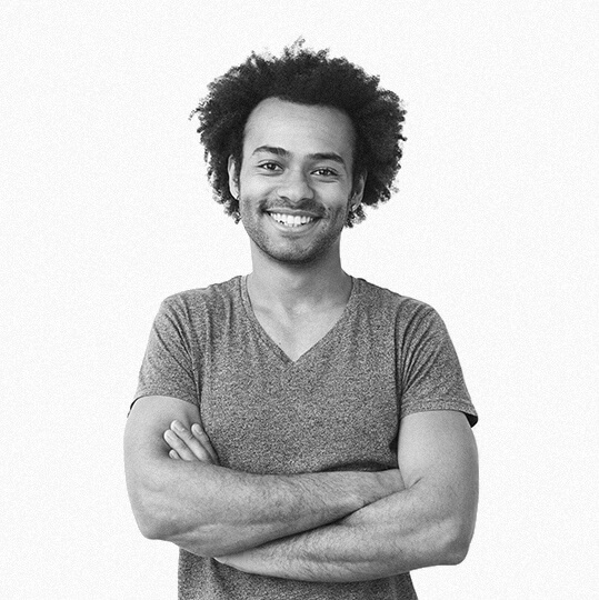Smiling man with curly hair and crossed arms in a casual t-shirt.