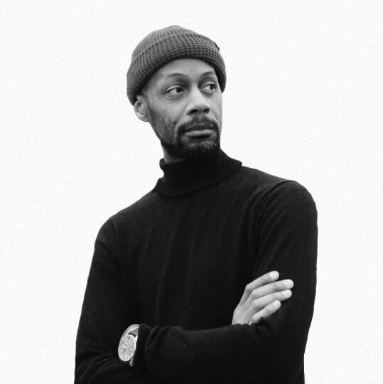Man in a black turtleneck and beanie looking thoughtfully to the side.