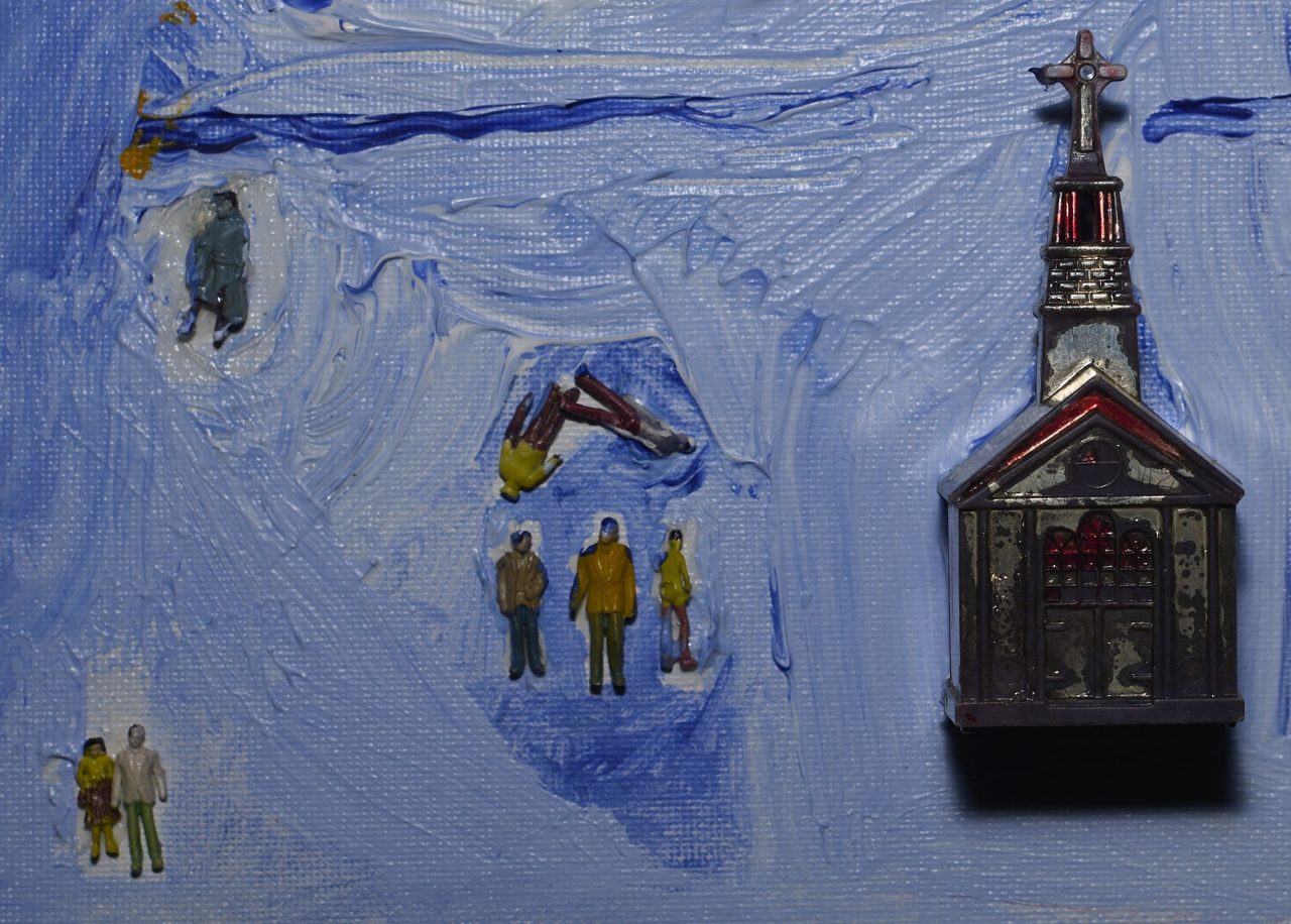 Miniature figures on a textured blue surface next to a small building model.