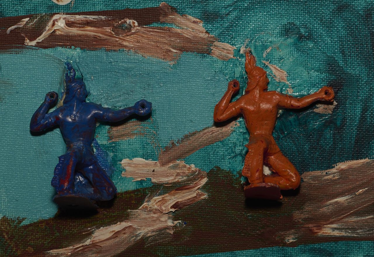 Two abstract clay figures posed against a textured blue and brown background.