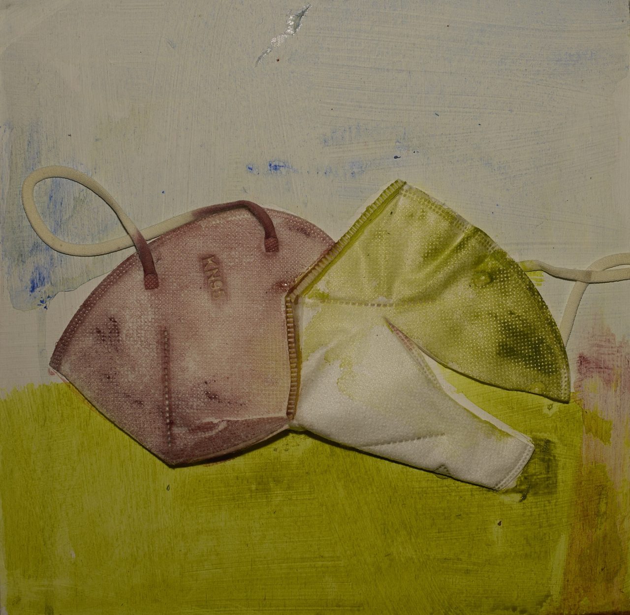 Two cloth face masks, one pink and one green, lying on a surface.