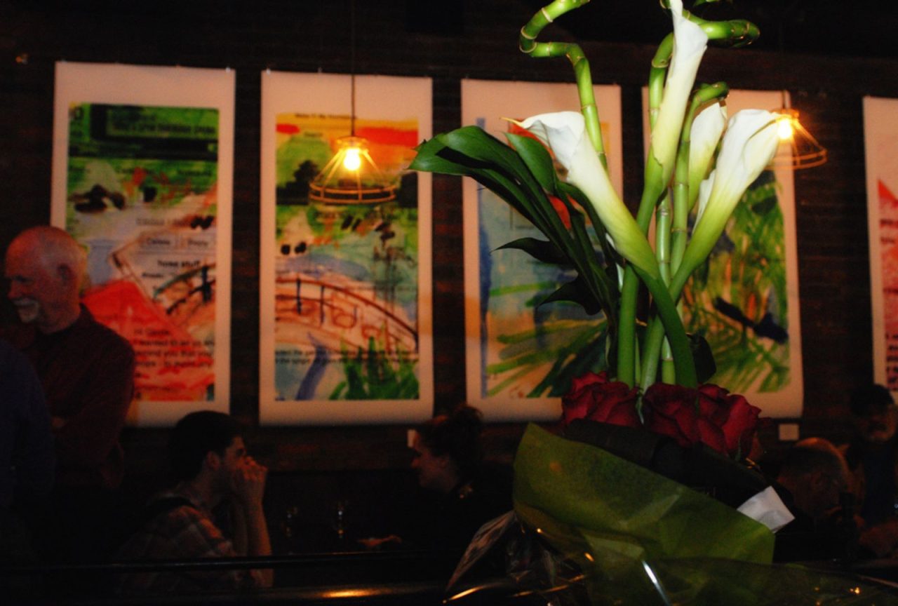 Dimly lit room with vibrant plant and colorful wall art.