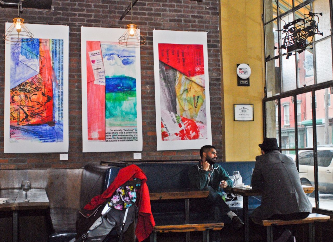 People dining in a cozy cafe with colorful paintings on the wall.